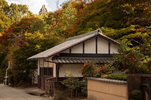 空き家管理サービス Serene traditional Japanese house surrounded by vibrant autumn foliage.